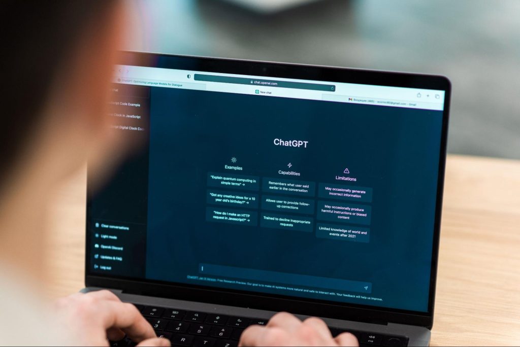 A man using the laptop, highlighting the Examples, Capabilities, and Limitations of ChatGPT on the screen.